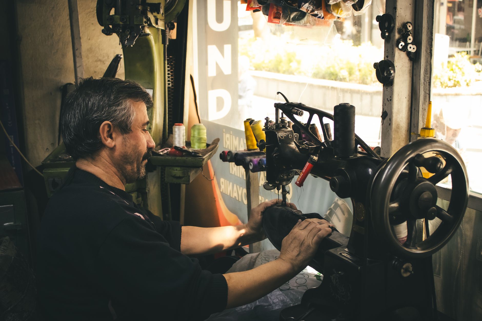 Hands repairing clothing at a community repair café, part of local UK clothing waste reduction initiatives